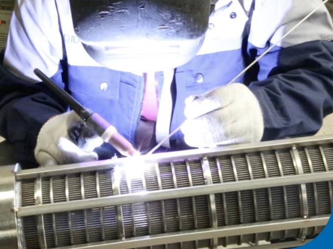 The worker is welding the wedge wire screen cylinder.